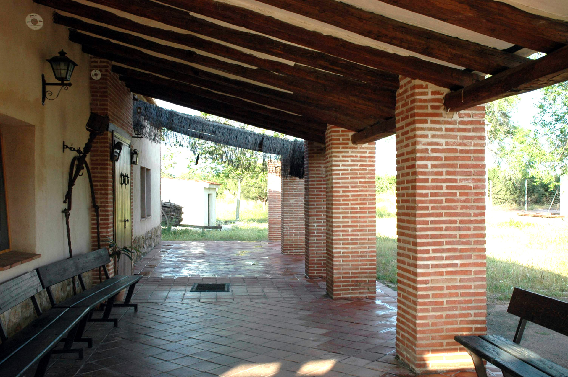 Porche de La Quinta de Melque con columnas de ladrillo y vigas de madera